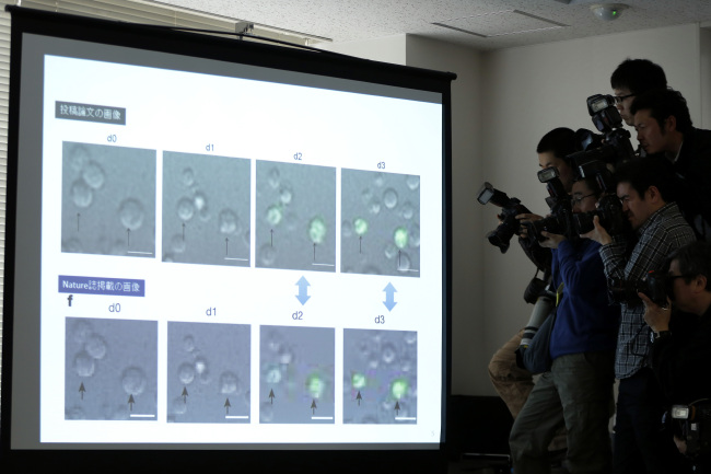 Photographers take pictures of images from an interim report on the research investigation into doubts about stem-cell findings in Tokyo.   Bloomberg