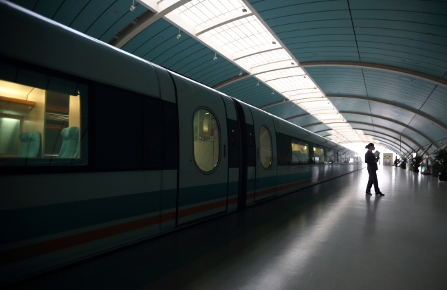 A station worker stands near a magnetic levitation train on the platform of the Long Yang Road station in Shanghai.   Bloomberg