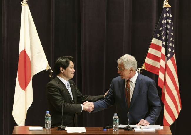 U.S. Secretary of Defense Chuck Hagel (right) and his Japanese counterpart Itsunori Onodera shake hands during a press conference in Tokyo on Sunday.   AP-Yonhap