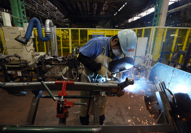 A worker welds an automobile part in the chassis manufacturing department at a Toyota Motor Corp. plant in Toyota City, Japan, Feb. 25.   Bloomberg