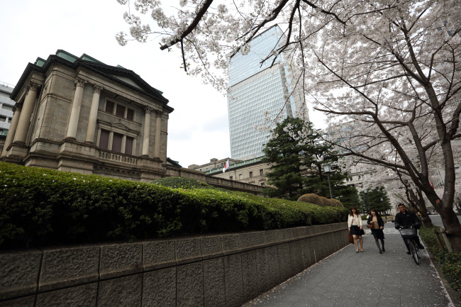 Pedestrians walk past the Bank of Japan headquarters in Tokyo, Japan, on Wednesday, April 2, 2014. Japan's inflation rate will be 1.5 percent in a year's time and 1.7 percent in three years and in five years, according to average forecasts in a Bank of Japan survey conducted from Feb. 24 to March 31. Photographer: Tomohiro Ohsumi/Bloomberg
Pedestrians walk past the Bank of Japan headquarters in Tokyo.   Bloomberg