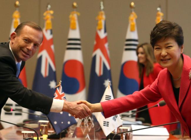South Korean President Park Geun-hye and Australian Prime Minister Tony Abbott shake hands after agreeing Tuesday to bolster security and defense cooperation between the two countries as their trade ministers signed an FTA. (Yonhap)