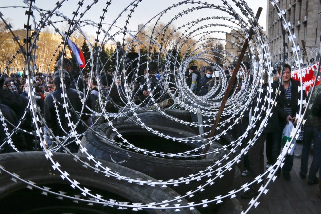 People gather near a barricade lined with razor wires at the regional administration building in Donetsk, Ukraine, Monday.   AP-Yonhap