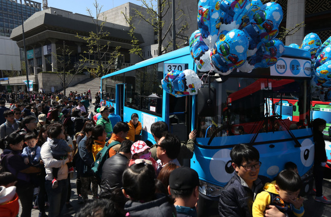 Children and parents lining up to board a Tayo character bus at Gwanghwamun Square in Seoul