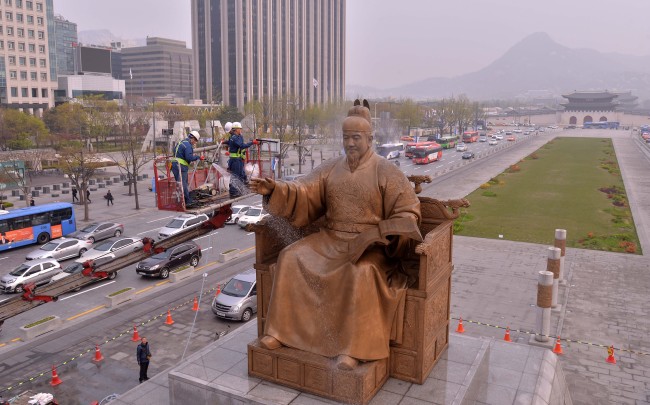 Seoul city government officials on Thursday hose down the statue of the Joseon era King Sejong the Great at Gwanghwamun Plaza in Seoul.   Lee Sang-sub/The Korea Herald