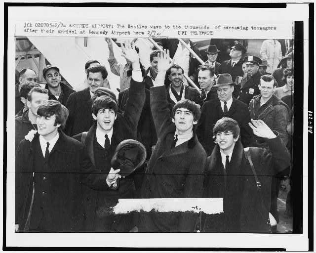 Front row, from the left: The Beatles member John Lennon, Paul McCartney, George Harrison and Ringo Starr wave hands at the fandom in Kennedy Airport, February 1964. (Wikimedia)