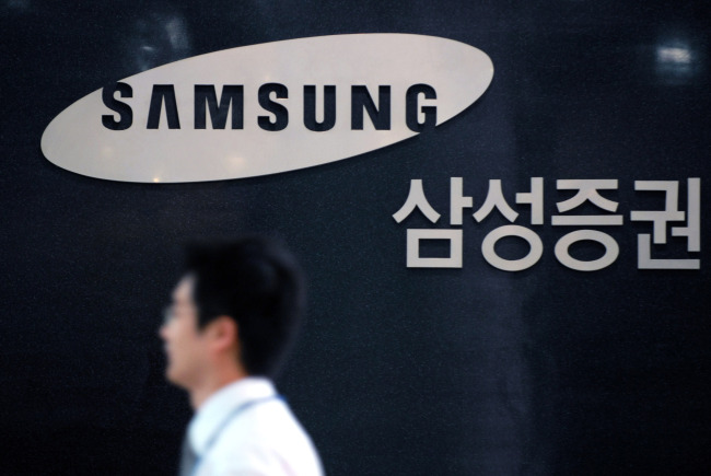 A Samsung Security Co. employee walks past the company's logo at its headquarters in Seoul, South Korea, on Wednesday, June 25, 2008. Samsung Security Co.'s Kim Hag Ju, head of research, was ranked No. 1 among all analysts in South Korea in Asiamoney's 2006 poll of investors. Photographer: Seokyong Lee/Bloomberg News
An employee of Samsung Securities, which announced a massive downsizing plan last Friday, walks past the company’s logo at its headquarters in Seoul.   Bloomberg