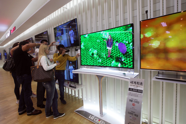 Customers take pictures of an LG Electronics curved OLED television in Seoul. Bloomberg