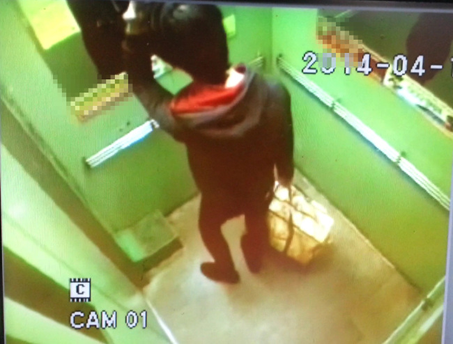 In this still from CCTV footage, a man who confessed to killing his infant son is seen leaving his apartment in Gumi, North Gyeongsang Province, Sunday, carrying the garbage bag supposedly containing the child’s body.   Yonhap