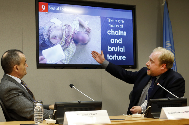 Forensic pathologist Dr. Stuart Hamilton (right) presents one of the photos in a series of what is reported to be photographic evidence of torture in Syria as Gerard Araud, France’s ambassador to the United Nations, looks on during a news conference at U.N. headquarters following a closed Security Council meeting on Tuesday.   AP-Yonhap