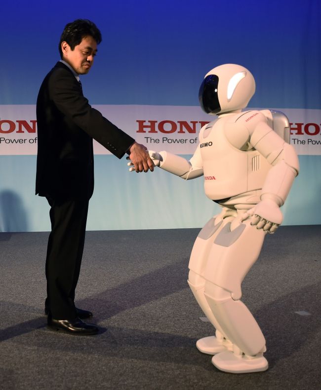 Honda’s Satoshi Shigemi interacts with ASIMO robot as Honda North America makes its North American debut of the robot at a news conference demonstration in New York.    AFP-Yonhap