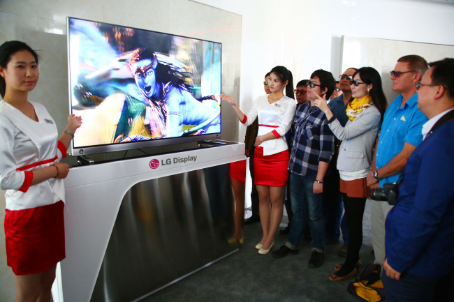 Visitors to LG Display’s pavilion installed at the venue of the 4th Beijing International Film Festival in Beijing watch 3-D content on LG Electronics’ 3-D UHD TV.   LG Display