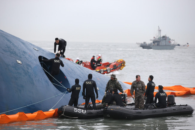 <YONHAP PHOTO-0466> <여객선침몰> 필사의 구조작업 (진도=연합뉴스) 특별취재팀 = 17일 오전 여객선 '세월호'가 침몰한 전남 진도군 조도면 병풍도 북쪽 3km 앞 사고 해상에서 해군 해난구조대(SSU)가 구조작업을 벌이고 있다. 2014.4.17 uwg806@yna.co.kr/2014-04-17 09:51:58/ <저작권자 ⓒ 1980-2014 ㈜연합뉴스. 무단 전재 재배포 금지.>
Rescue workers mount the hull of the Sewol on Thursday.   Yonhap