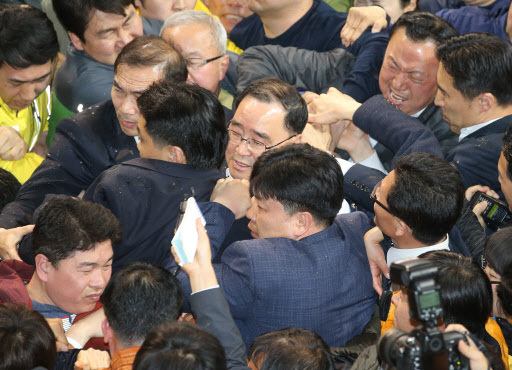 Prime Minister Chung Hong-Won tries to make his way out of a gymnasium in South Jeolla Province early Thursday, after family members of Sewol victims throw objects and tear at his clothing to keep him from leaving (Yonhap)