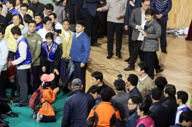 The mother of a child trapped in the sunken ferry Sewol kneels and pleads for stronger rescue efforts as President Park Geun-hye visits passengers’ families at a gymnasium in Jindo, South Jeolla Province, Thursday. (Yonhap)