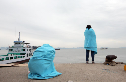 Families of the missing students from the capsized Sewol ferry stare at the sea from Jindo Port in South Jeolla Province on Thursday. (Yonhap)