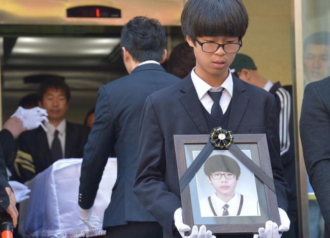 A 17-year-old victim’s brother holds a picture of his sibling at a funeral service in Ansan, Gyeonggi Province, Monday.   Yoon Byung-chan/The Korea Herald