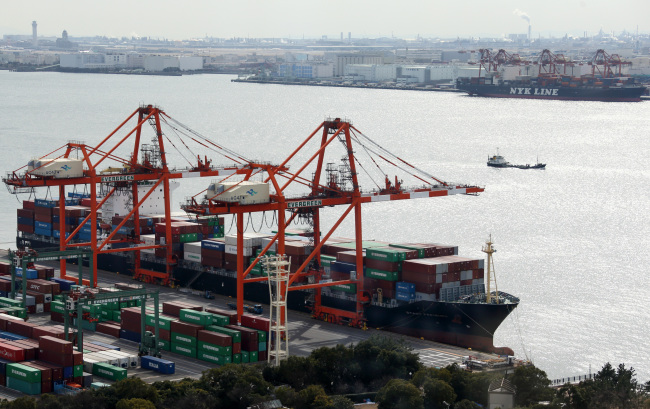 A container ship sits berthed next to gantry cranes at a shipping terminal in Tokyo.   Bloomberg