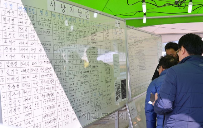 세월호 침몰사건이 일어난지 엿새째인 21일 오전 전남 진도군 팽목항에 설치된 사망자관련 정보게시판을 실종자 가족이 살펴보고 있다.