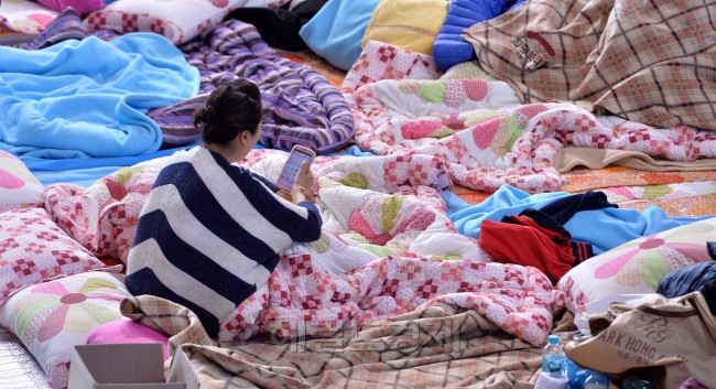 세월호가 침몰한지 엿새째인 21일 오전 실종자가족들이 전남 진도군 진도실내체육관에 마련된 임시거처에서 생존자 구조를 기다리며 휴대전화를 보고 있다.