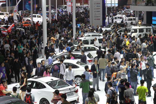 Visitors gather to look at the cars on display during the “Auto China 2014” Beijing International Automotive Exhibition in Beijing on Monday.    AFP-Yonhap