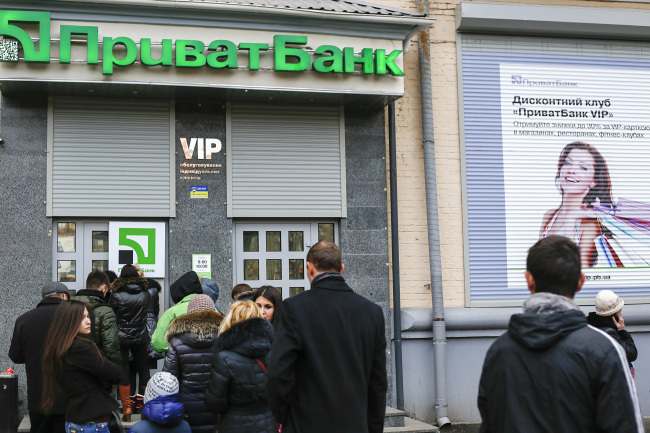 Customers lineup to withdraw money from an ATM outside a Privatbank CJSC bank branch in Kiev.   Bloomberg