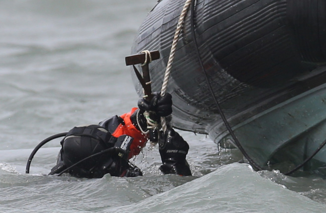 A diver carrying a hammer enters the water to search for missing passengers of the sunken Sewol off the coast of Jindo Island, South Jeolla Province, Tuesday. Yonhap