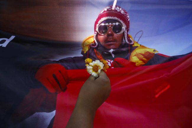 A flower is held up in front of a picture of a Nepalese mountaineer, one of the victims of a recent Mount Everest avalanche, during a cremation ceremony at Syambhu in Kathmandu on Monday.   EPA-Yonhap
