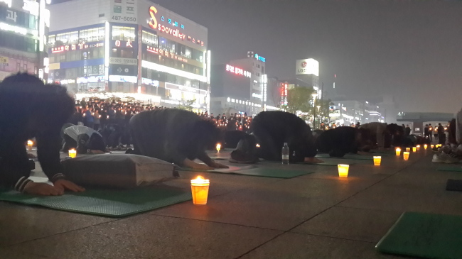 23일 저녁 8시께 경기 안산시 고잔동 문화광장에서 열린 촛불기도회에 참가한 시민 100여명이 세월호 침몰사고 희생자 추모와 무사귀환을 기원하는 50배를 올리고 있다.