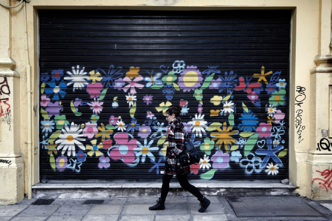 A pedestrian passes the shutters of a closed store in Thessaloniki, Greece.   Bloomberg