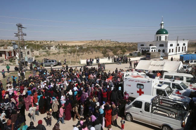 Syrian and Lebanese citizens gather to receive aid supplies at the main square of Tfail village at the Lebanese-Syrian border, eastern Lebanon, Tuesday.   AP-Yonhap