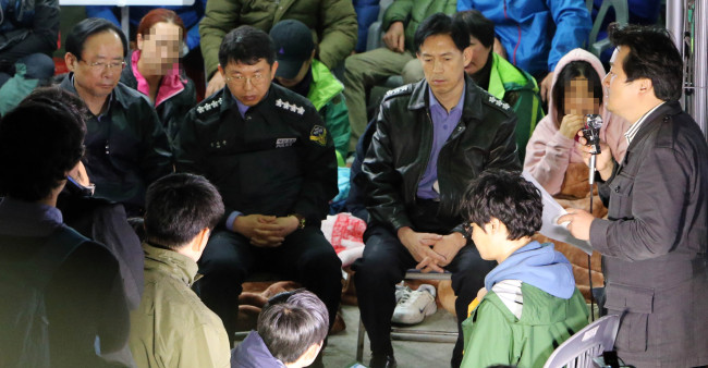 Oceans and Fisheries Minister Lee Ju-young (left) and Coast Guard chief Kim Seok-kyun (second from left) meet with family members of the sunken ferry Sewol’s missing passengers at a port on Jindo Island, South Jeolla Province, Thursday.   Yonhap