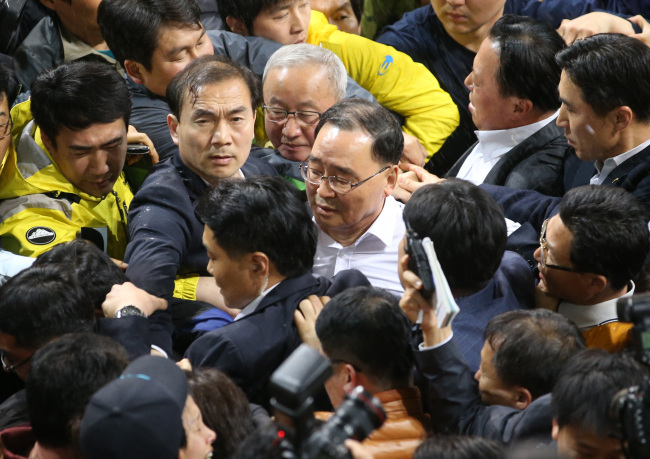Prime Minister Chung Hong-won (center) faces protests from families of missing passengers in the sinking of the ferry Sewol during his visit to their shelter at a gym on Jindo Island, South Jeolla Province, April 17.   Yonhap