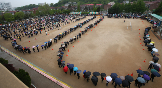 Mourners line up to visit the memorial altar in Ansan, Gyeonggi Province, Sunday. The playing field of a neighboring public school was used to accommodate the large number of visitors.   Yonhap