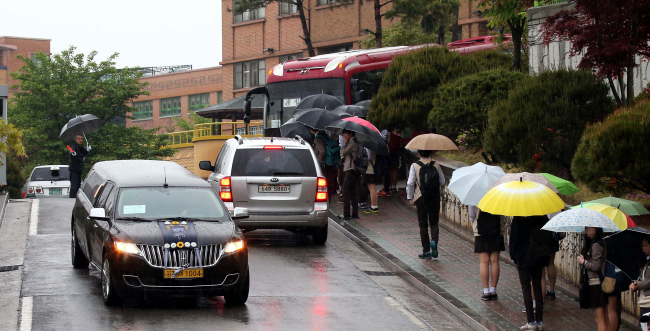 A hearse drives past students at Danwon High School in Ansan, Gyeonggi Province, Monday, when classes resumed for the school’s first- and second-year students.   Joint Press Corps