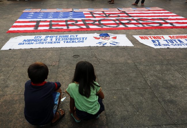 Filipino children observe a mock U.S. flag and banners during a protest rally against U.S. President Barack Obama’s visit in Manila on Monday.   EPA-Yonhap