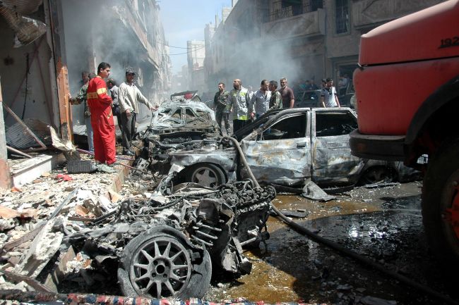 Emergency personnel and civilians inspect the site following a car bomb explosion in the Abbasiyah neighborhood of Homs, central Syria, Tuesday.   AFP-Yonhap
