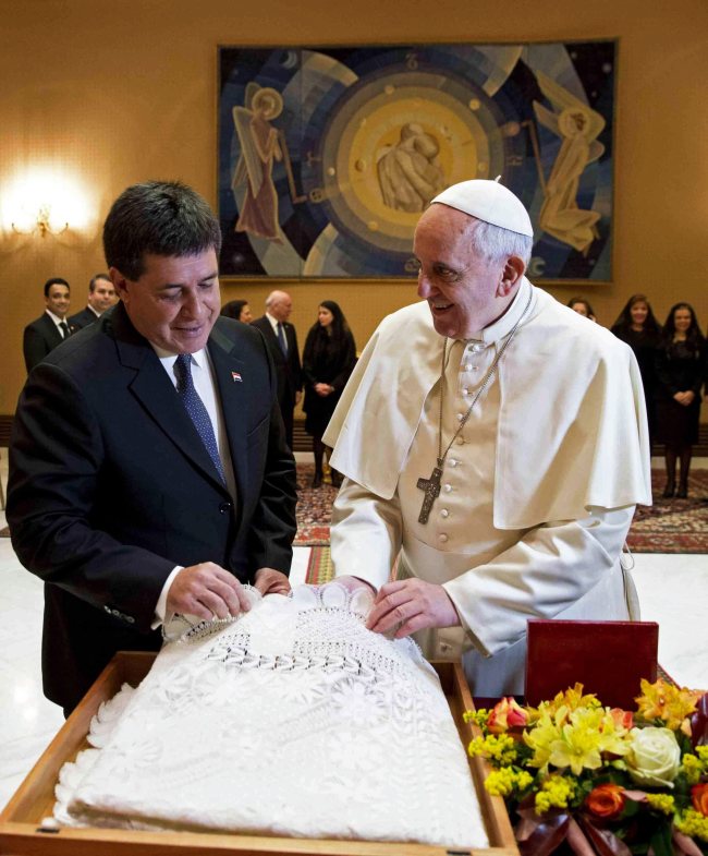 Pope Francis (right) is presented with a gift by Paraguayan President Horacio Cartes during a private audience at the Vatican on Tuesday.   EPA-Yonhap