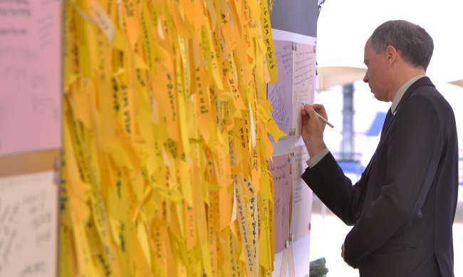 British Ambassador Scott Wightman writes a condolence message at a memorial altar set up in Seoul Plaza on Friday.   Lee Sang-sub/The Korea Herald