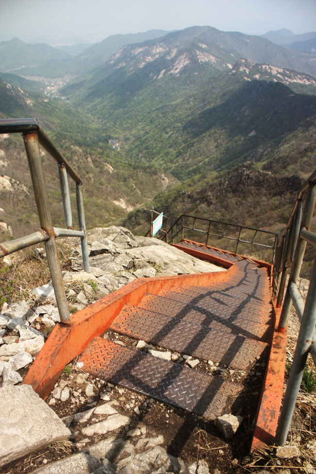 From the top of a set of stairs near Gwaneumbong Peak, the view extends from Donghaksa Valley to Daejeon in the far distance. (Matt Crawford/The Korea Herald)