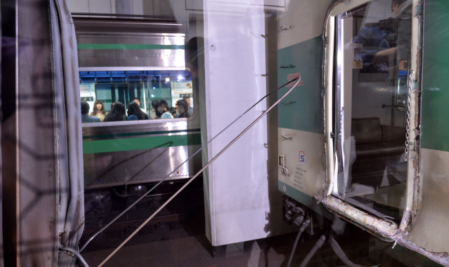 Passengers look at subway cars separated after a collision at Sangwangsimni Station in Seoul on Friday. (Lee Sang-sub/The Korea Herald)