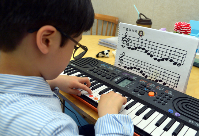Kim Un-o, a 7-year-old elementary school student, uses colored stickers to learn the piano at the Dalgona Music Institute in Banpo-dong, southern Seoul.   Yoon Byung-chan/The Korea Herald