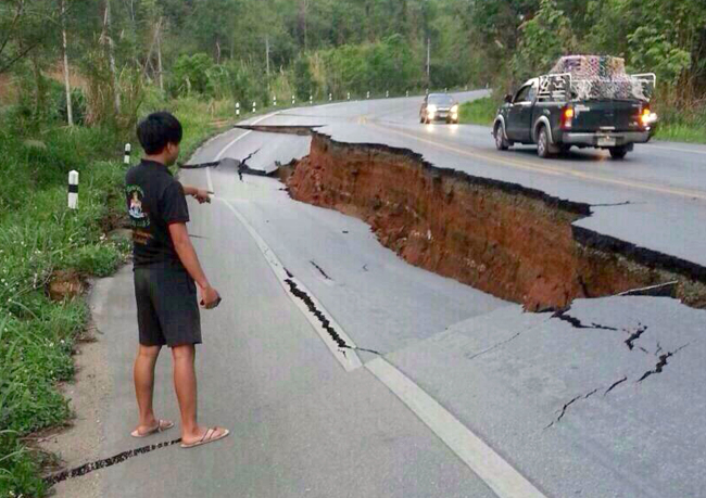 A man points to a big crack on a damaged road following a strong earthquake in Phan district of Chiang Rai province, northern Thailand, Monday.   AP-Yonhap