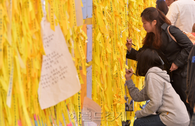 부처님오신날인 6일 오전 서울광장에 마련된 세월호 희생자 합동 분향소와 '노란리본의 정원'을 방문한 시민이 추모의 의미로 노란 리본을 매달고 있다.<br />이상섭 기자. bqbtong@heraldcorp.com
