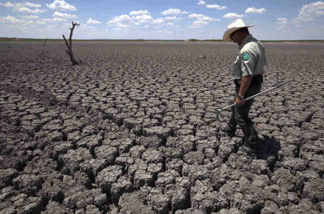 A police officer walks across the cracked lake bed of O.C. Fisher Lake in San Angelo, Texas.   AP-Yonhap