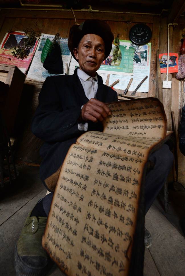 Chinese shaman Zhao Fucheng thumbs through an ancient text said to predict the future at his Qiuka village home in Guangxi province.   AFP-Yonhap
