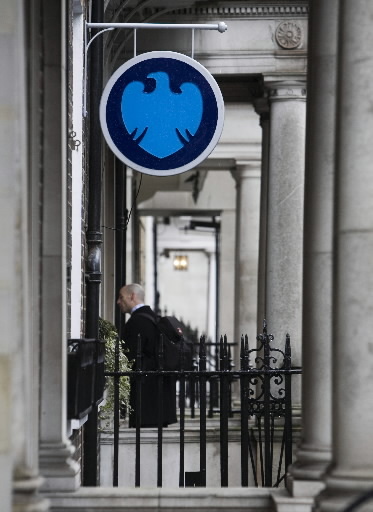 A pedestrian walks under a sign outside a Barclays bank branch in London.   Bloomberg