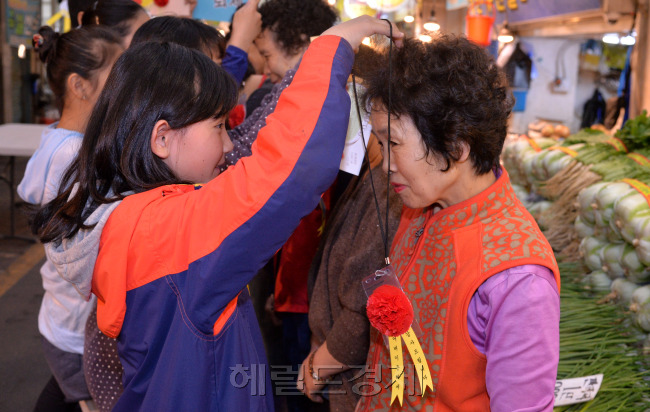 어버이 날인 8일 오전 경기도 광명시 광명전통시장에서 광명초등학교 어린이들이 손수 만든 카네이션을 전통시장 상인들에게 달아주는 광명 반짝이 사랑의 카네이션 달아주기 행사가 열렸다.<br />이상섭 기자. babtong@heraldcorp.com
고사리 손이 빚은 카네이션