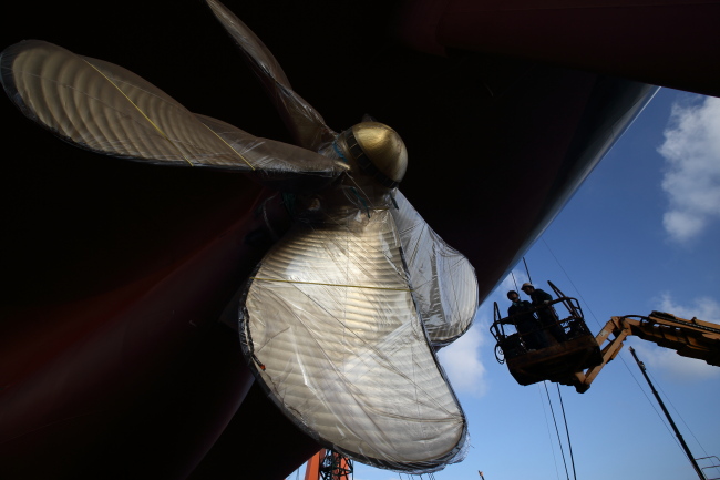 Employees work on an elevated work platform near the propeller of a ship under construction at the Hyundai Samho Heavy Industries Co. shipyard in Yeongam, South Jeolla Province.   Bloomberg