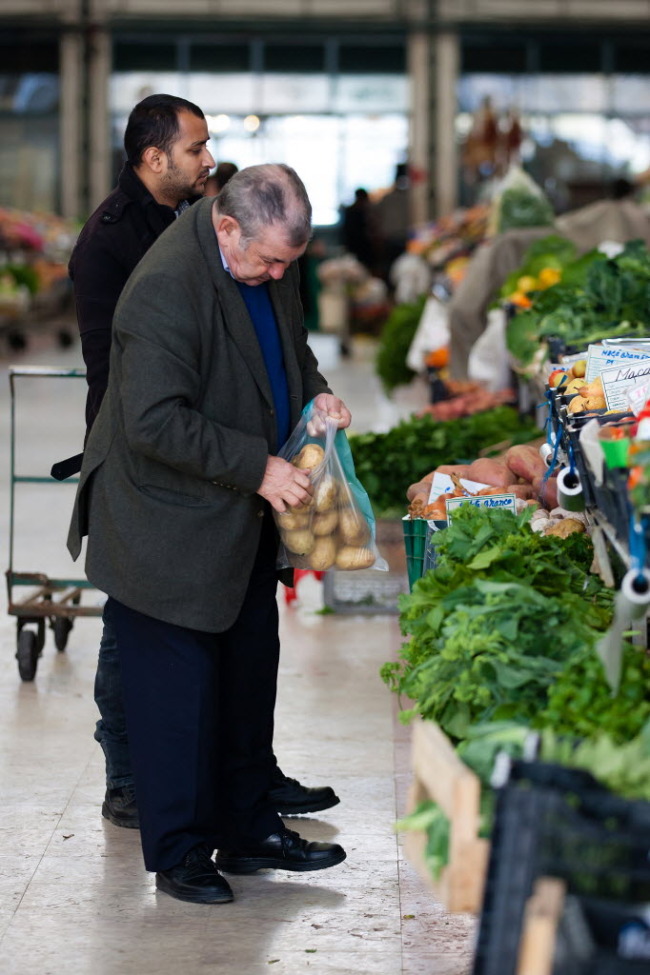 An elderly  customer selects potatoes from a stall at Ribeira market in Lisbon.   Bloomberg